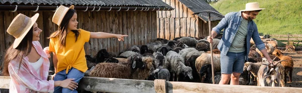 Fille en chapeau de paille pointant vers papa travaillant avec le troupeau dans le corral, bannière — Photo de stock