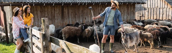 Mother and daughter looking at man working with livestock in corral, banner — Stock Photo