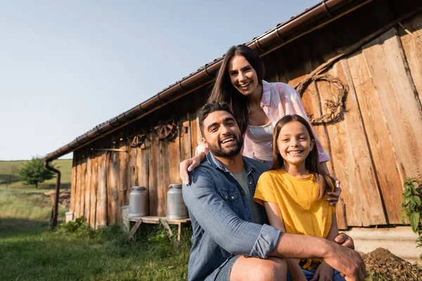 Jubelnde Bauern mit Tochter blicken auf Bauernhof im Dorf in die Kamera — Stockfoto