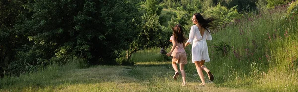 Full length of mom and daughter running on grassy path in countryside, banner — Foto stock