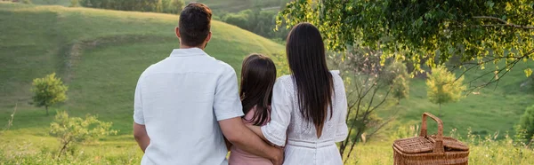 Vista para trás da família sentada na frente da paisagem cênica no campo, bandeira — Fotografia de Stock