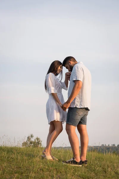 Pleine longueur de l'homme baisant la main de la femme tout en se tenant face à face dans le champ — Photo de stock