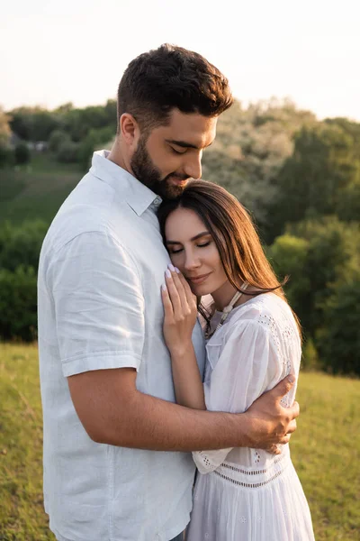 Donna felice con gli occhi chiusi appoggiati sul petto di uomo barbuto all'aperto — Foto stock