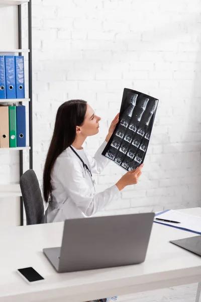 Side view of doctor looking at mri scan near devices on table in clinic — Fotografia de Stock