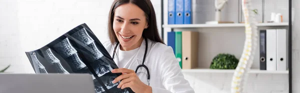 Fröhlicher Arzt zeigt MRI-Scan beim Videoanruf am Laptop in der Klinik, Banner — Stockfoto