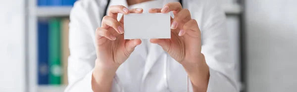 Vista recortada del médico borroso que sostiene la tarjeta de visita vacía en el hospital, pancarta - foto de stock