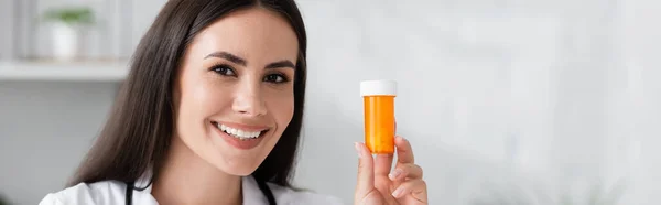 Positive doctor holding pills in hospital, banner — Stock Photo