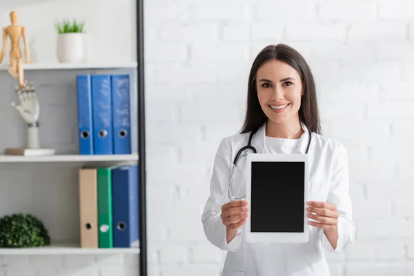 Brunette médecin en manteau blanc tenant tablette numérique en clinique — Photo de stock