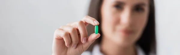 Blurred doctor holding green pill in hospital, banner — Stock Photo