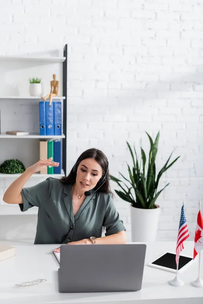 Professeur en gestuelle casque pendant la leçon en ligne sur ordinateur portable en classe — Photo de stock