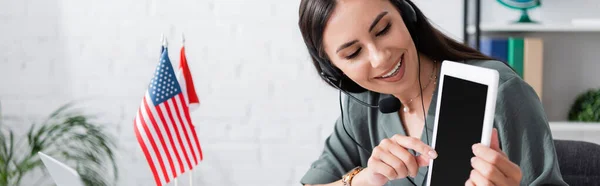 Teacher in headset holding digital tablet during online lesson on laptop in school, banner — Fotografia de Stock