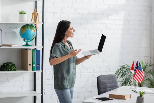 Side view of teacher pointing at laptop during video call in class — Foto stock