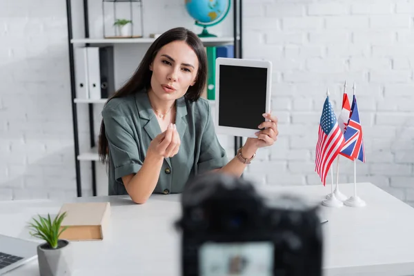 Insegnante in possesso di tablet digitale e parlando vicino alla fotocamera e bandiere in classe — Foto stock