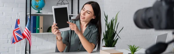 Lehrer zeigt auf digitales Tablet in der Nähe der Kamera und Flaggen von Ländern in der Schule, Banner — Stockfoto