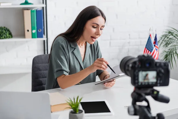 Tutor holding notebook near devices and digital camera in class — Stock Photo