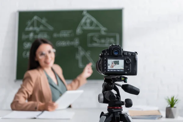 Digital camera near blurred teacher in classroom — Fotografia de Stock