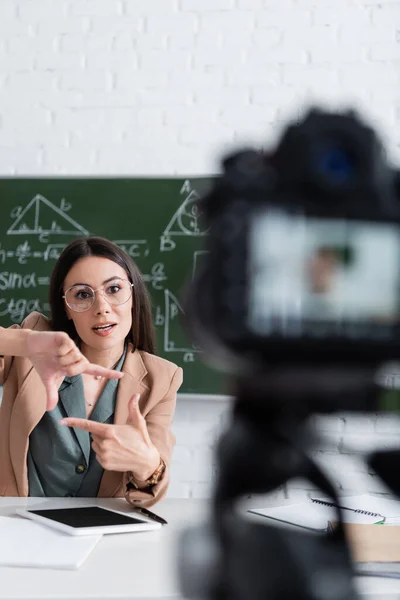 Lehrer mit Brille gestikuliert neben digitalem Tablet und Kamera im Klassenzimmer — Stockfoto