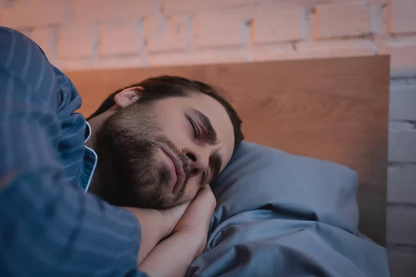 Joven con los ojos cerrados acostado en la cama - foto de stock