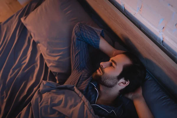 Side view of man with sleep disorder lying on bed at home — Stockfoto