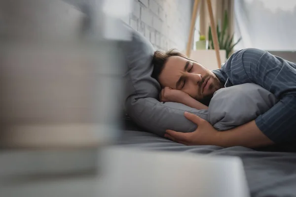 Joven durmiendo en la cama en casa por la mañana - foto de stock