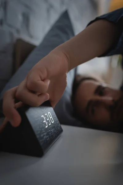 Розмитий чоловік бере електронний годинник з тумбочки вночі — стокове фото