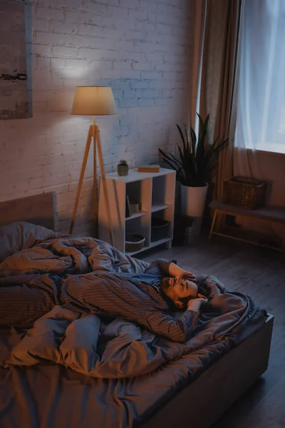 Young man with sleep disorder lying on bed at night — Photo de stock