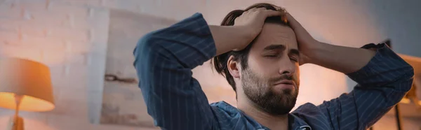Junger Mann berührt Kopf, während er zu Hause an Schlaflosigkeit leidet, Banner — Stockfoto