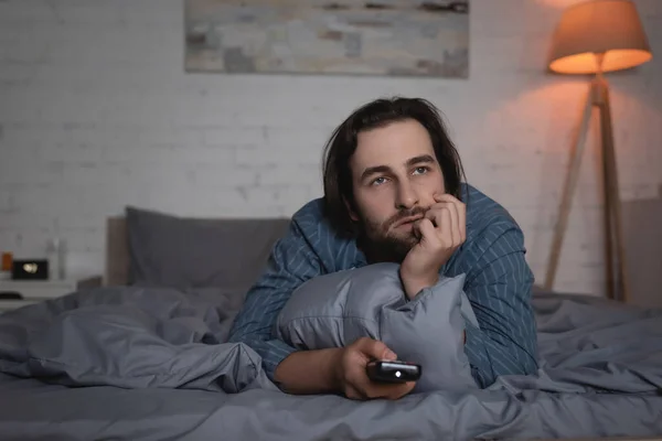 Man with sleep disorder watching movie on bed at night - foto de stock