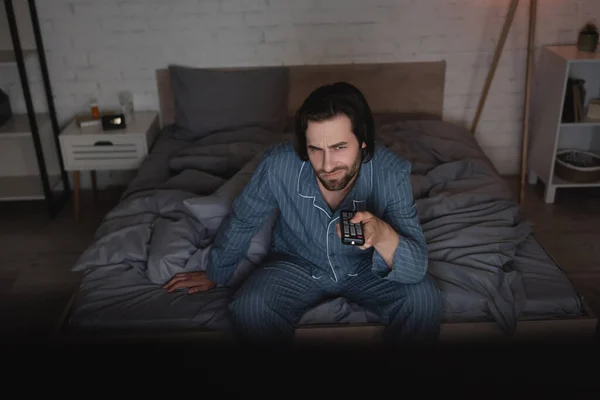 Hombre disgustado con insomnio viendo películas en el dormitorio por la noche - foto de stock