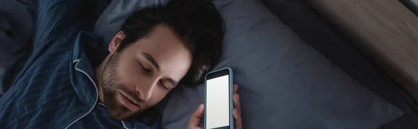 Visão superior do homem segurando smartphone enquanto dorme na cama, banner — Fotografia de Stock