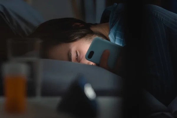 Man with sleep disorder using smartphone on bed at night — Stock Photo