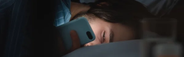 Man looking at smartphone on bed at night, banner — Foto stock