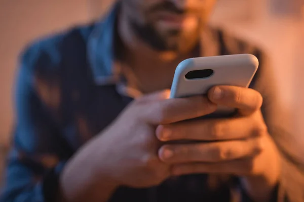 Cropped view of blurred man with insomnia using cellphone in bedroom — Stock Photo