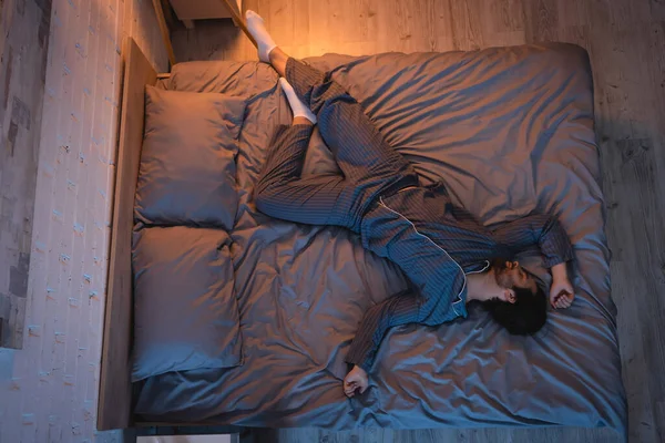 Вид сверху на молодого бородатого человека, спящего дома на кровати — стоковое фото