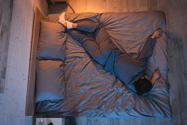 Seitenansicht eines Mannes in Pyjama und Socken, der im Schlafzimmer schläft — Stockfoto