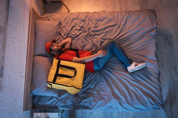 Vista superior del sonámbulo en uniforme de entrega durmiendo en la cama por la noche - foto de stock