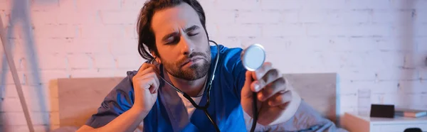 Sleepwalker in doctor uniform holding stethoscope in bedroom at night, banner — Stock Photo