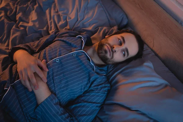 Top view of young man in pajama suffering from sleep disorder on bed - foto de stock