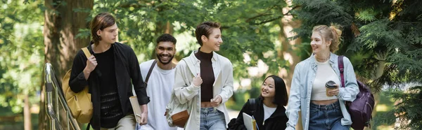 Interracial students with backpacks walking in summer park, banner — Stock Photo