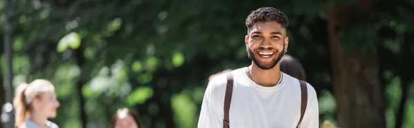 Allegro studente afroamericano che guarda la fotocamera nel parco estivo, striscione — Foto stock