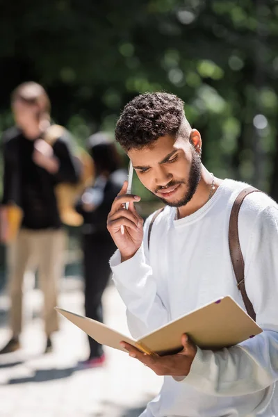 Страшный африканский студент-американец держит ручку и блокнот снаружи — стоковое фото