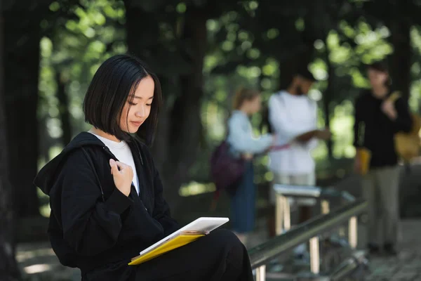 Studente asiatico utilizzando tablet digitale nel parco — Foto stock