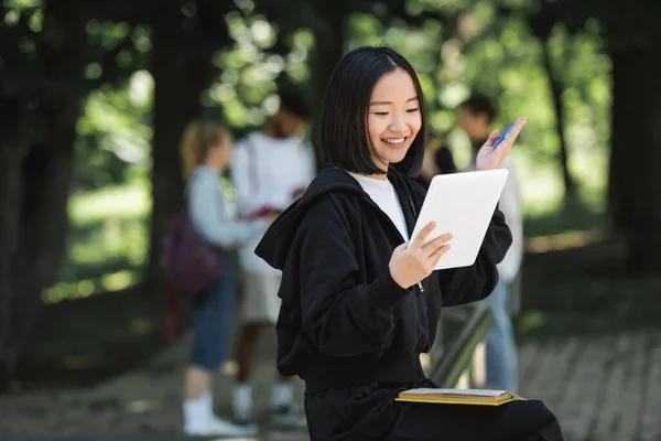 Positivo asiático estudiante tener vídeo llamada en digital tablet en parque — Stock Photo