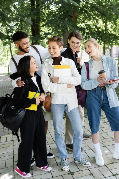 Cheerful multicultural students with copy books and backpacks spending time in park — Stockfoto