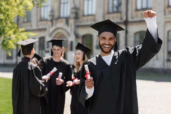 Eccitato scapolo afroamericano in possesso di diploma vicino amici nel parco — Foto stock