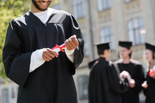 Cropped view of smiling african american bachelor holding diploma in park — Stock Photo