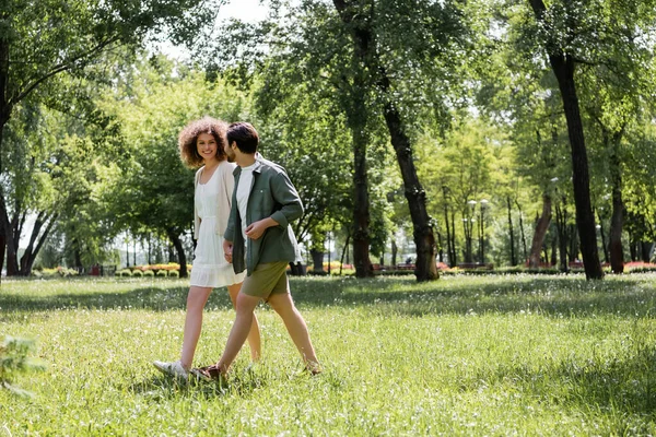 Full length of happy young couple having date while walking in green park — Photo de stock
