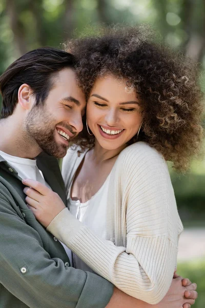 Jovem alegre sorrindo e abraçando mulher feliz e encaracolado — Fotografia de Stock