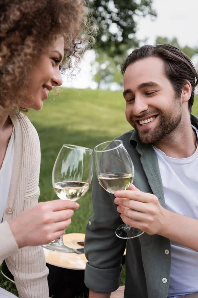 Happy young couple clinking glasses of wine during picnic - foto de stock