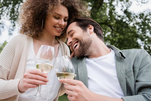 Homme heureux et femme gaie tenant des verres de vin dans le parc — Photo de stock